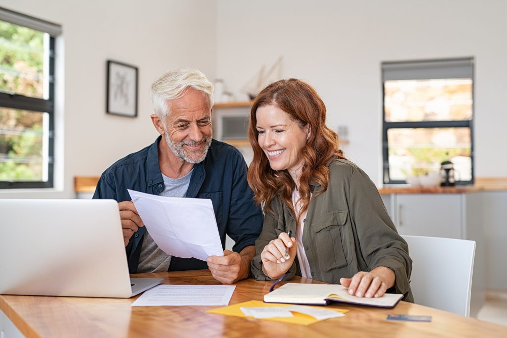 Mature smiling couple sitting and managing expenses at home