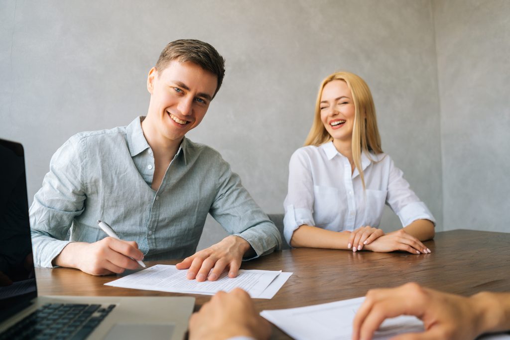 Smiling millennial family feeling happy about agreement they have to sign a contract